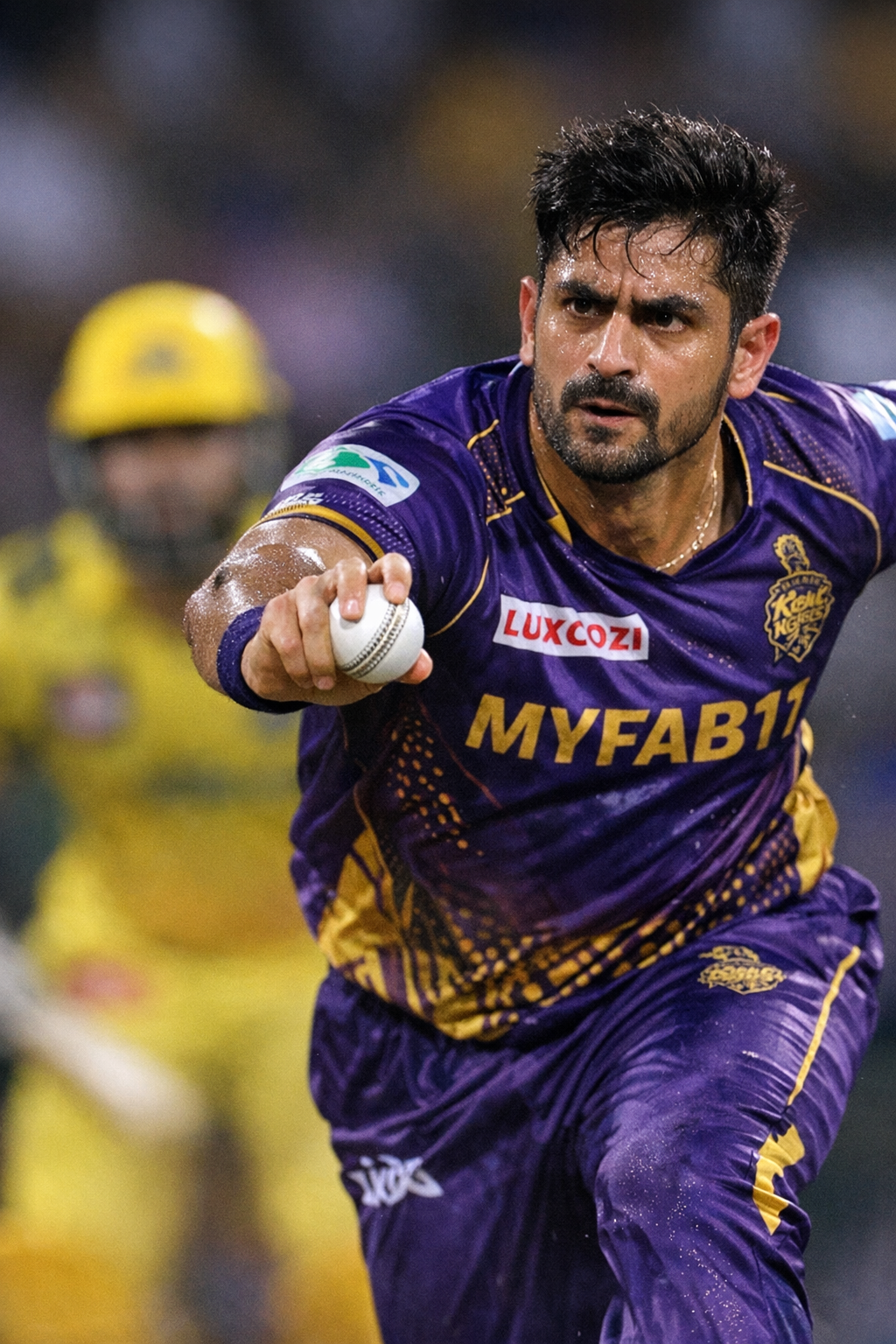 KKR fast bowler in action, ball release against CSK batter under IPL stadium lights.